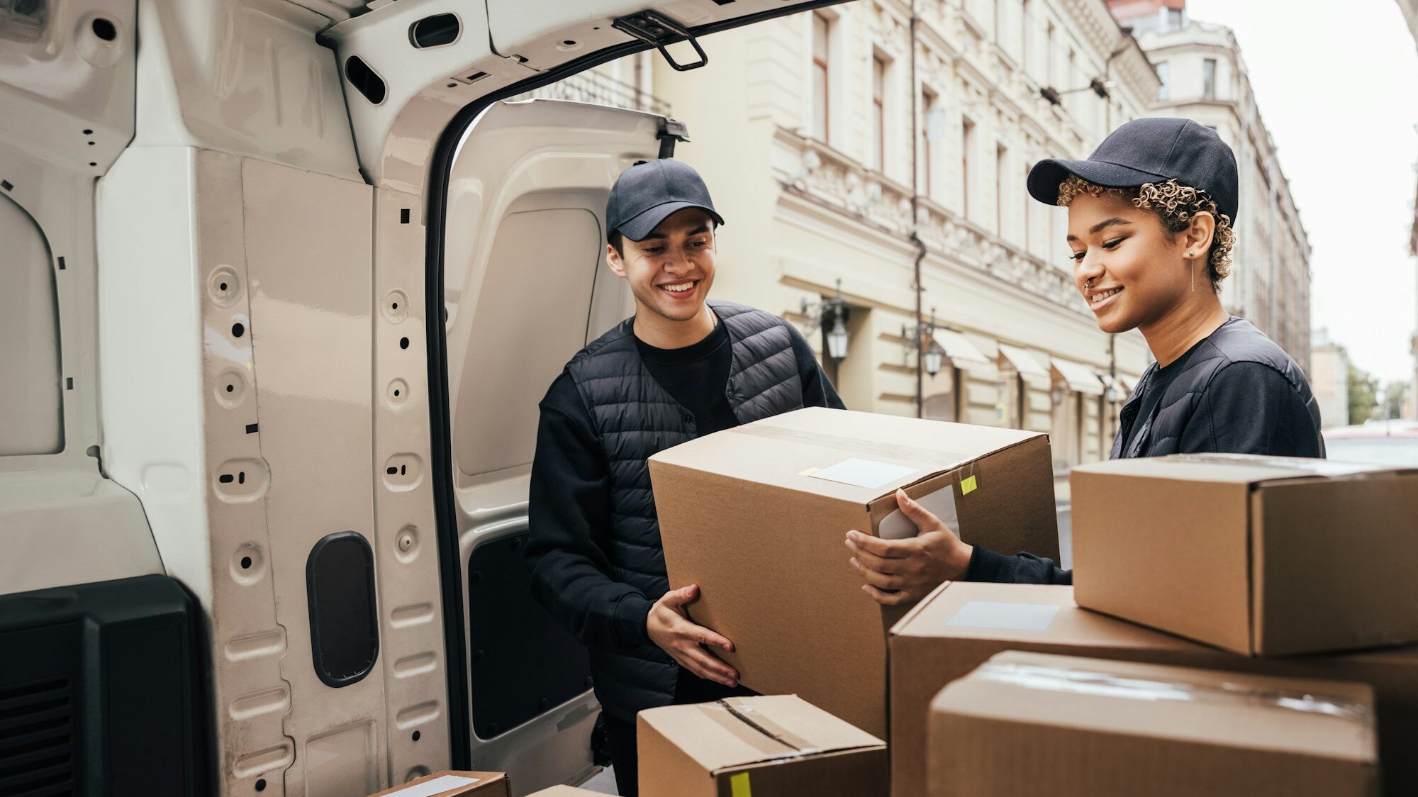 People working for a delivery company. Couriers load packages into a car.